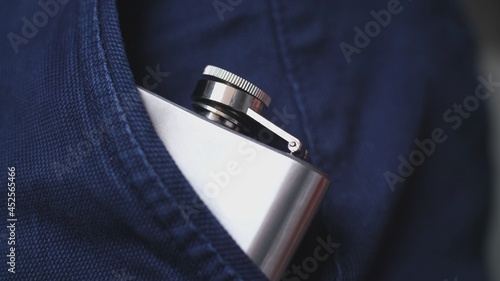 Caucasian Drinking Man Keeping Shiny Metal Hip Flask of Whiskey Alcohol Concealed in Trousers Pocket photo