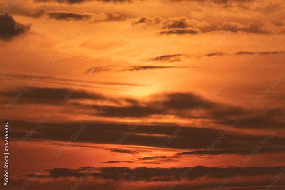 Clouds and atmosphere in warm evening colors with the sun behind the clouds
