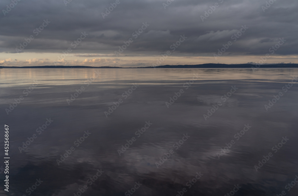 Beautiful autumn misty grey lake and cloudy sky reflection in the water at sunset. Dark and moody nature background. Great wallpaper design. Copy space.