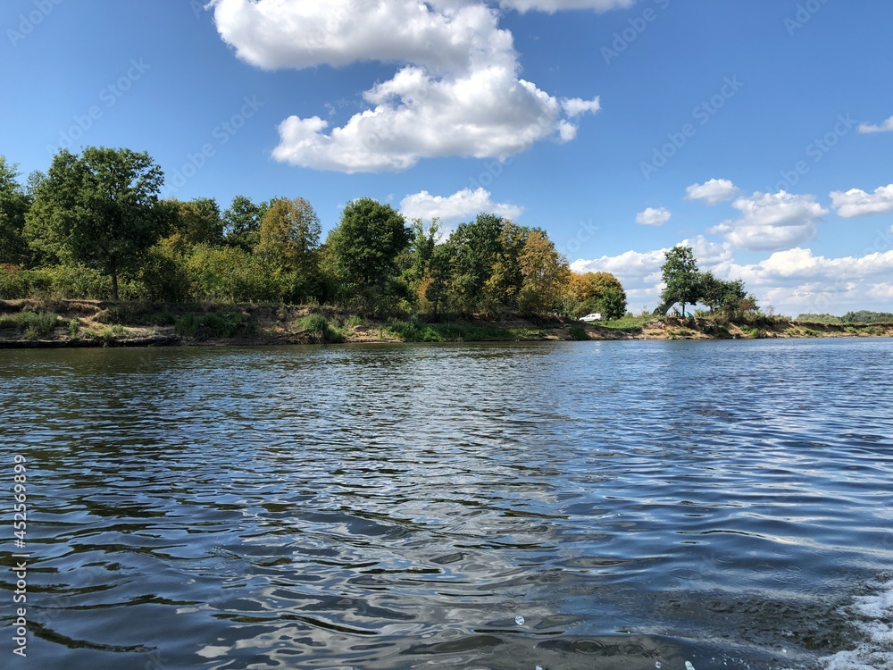 Bank of the river against a background of blue sky with white clouds. Bank of the river against a background of blue sky with white clouds.
