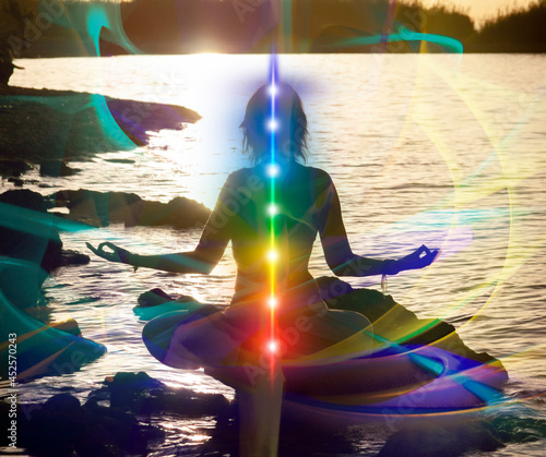 Glowing seven all chakra. Yoga meditation outdoors. Woman sits in a Lotus pose on mountain river view, Kundalini energy. girl zen practicing.