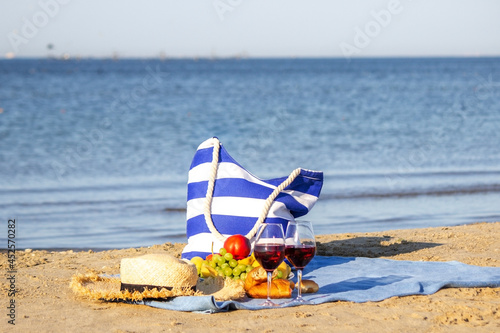 Fototapeta Picnic blanket, wine, fruit, beautiful sea beach Nature Selective focus