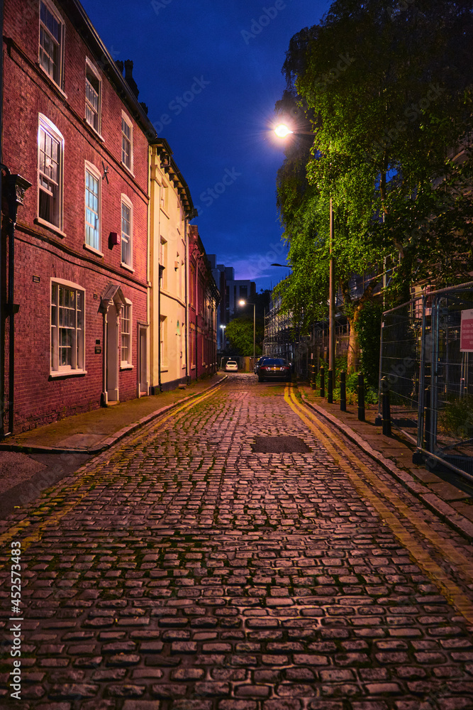 shiny, beautiful, stone paved historic street in evening. surounded by colours and dark blue sky.