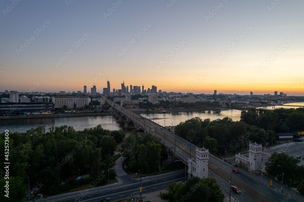 wieżowce w cetrum Warszawy, rzeka Wisła, most Poniatowskiego o zachodzie słońca z lotu ptaka, dron
