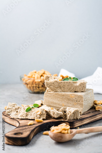 Pieces of sunflower and peanut halva and mint leaves on a cutting board on the table. Caloric oriental dessert. Vertical view photo