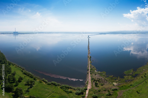 Beryozovskoye reservoir - cooling reservoir of Beryozovskaya GRES. Aerial drone view of lake landscape with road in sunny summer. Berezovskaya GRES is a thermal power plant in the town of Sharypovo