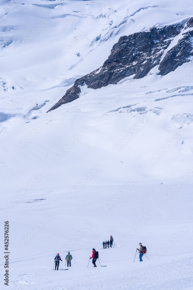 un groupe de randonneurs en plein trek au milieu d'un glacier dans les alpes suisses