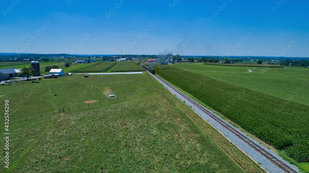 Aerial View of a Steam Locomotive Traveling Across a Fertile Farmland Landscape on a Beautiful Summer Day