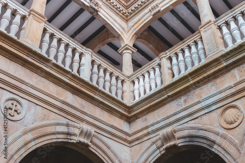 Facade of medieval church with shell and cross details. Old church on Camino de Santiago, Spain. Symmetry in ancient architecture details. Religious architecture. Courtyard of gothic cathedral. 