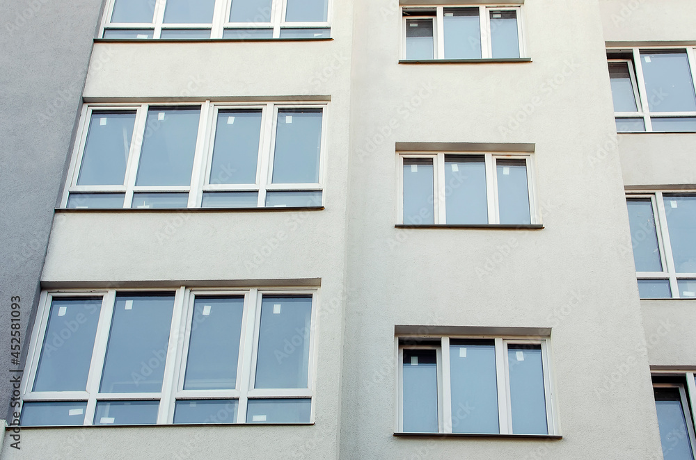 Close-up of the facade of a multi-storey residential building. Windows on the wall.