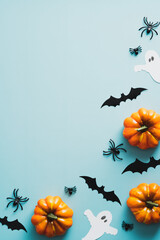 Happy halloween holiday concept. Frame of halloween decorations, bats, ghosts, pumpkins, spiders on blue background. Halloween party invitation card mockup with copy space. Flat lay, top view.