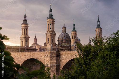 Cathedral Basilica of Our Lady of Pillar with bridge and trees at Zaragoza.