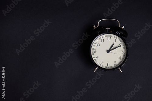 Flat lay. Monochrome composition with a vintage alarm clock on black background with copy space to add text. Back to School and Teachers Day Concepts, Business, Organization, Time Management