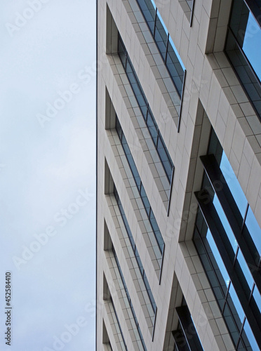angled close up of a modern office building with blue cloudy sky