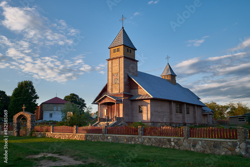 Old wooden catholic Church of the Virgin Mary the Gueen in Porplishche, Dokshitsy district, Vitebsk region, Belarus. Wooden temple in the light of setting sun. photo