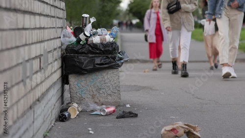 garbage, people throw out garbage, full bins, garbage lying on the streets of the city. people walk past garbage