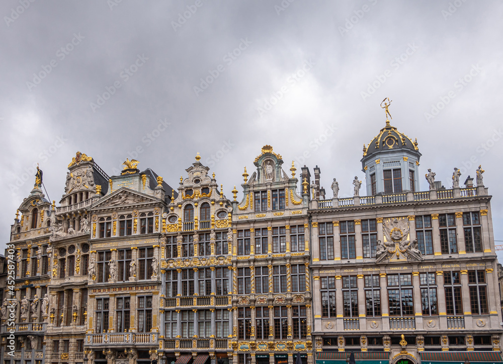 Brussels, Belgium - July 31, 2021: 6 historic iconic facades of guild houses on NW-side of Grand Place under heavy gray cloudscape. Lots of sculptures and golden ornaments.
