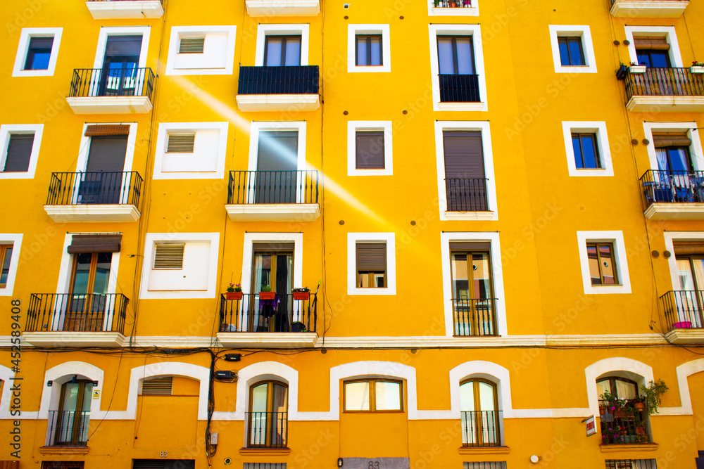 Vivid yellow apartment block building in Barcelona in the bright sunlight on a warm summers day. Strong blue sky behind it with a nice contrast