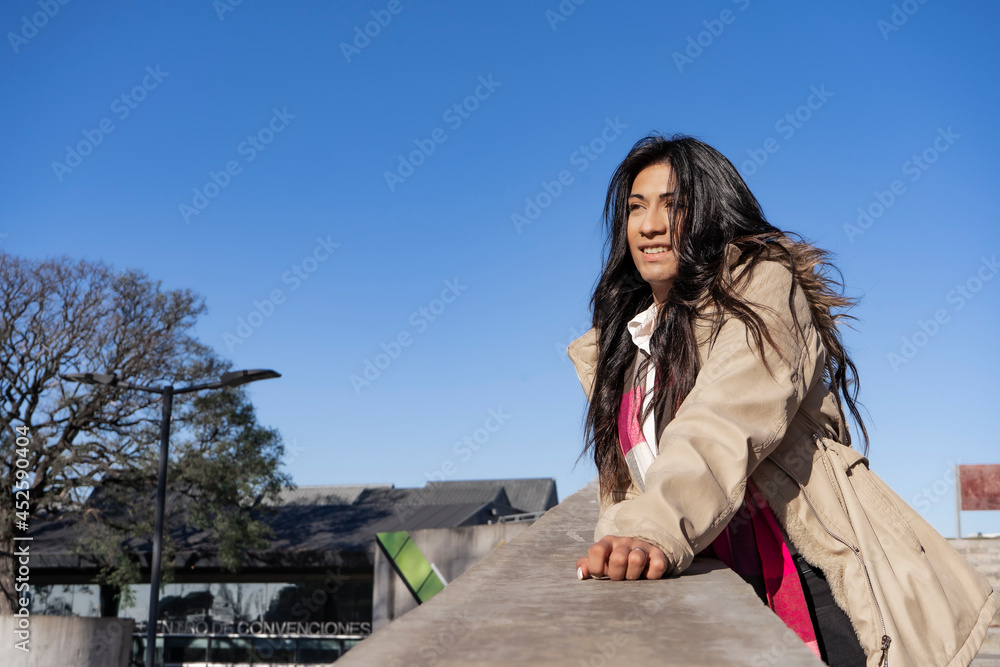 Beautiful Latin woman with a happy smile leaning on a concrete railing.