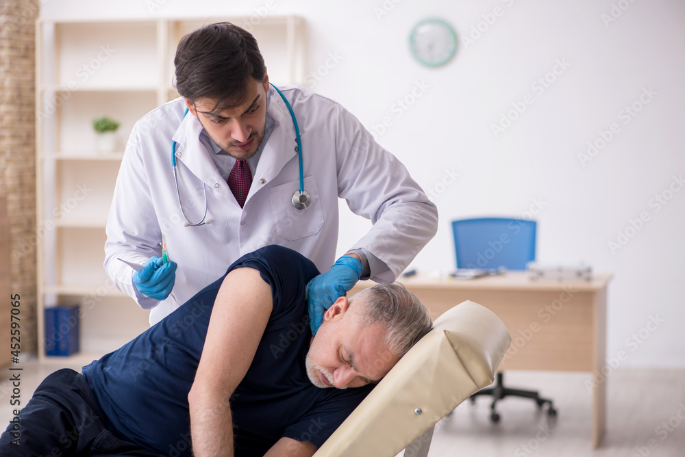 Fototapeta premium Old male patient visiting young male doctor in vaccination conce
