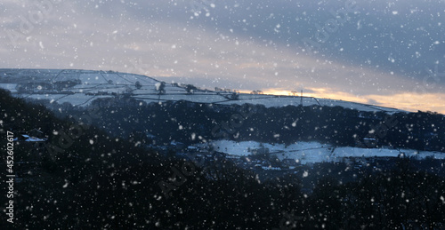 panoramic view of a glowing orange sunset in a cloudy twilight winter sky with falling snow in calderdale west yorkshire © Philip J Openshaw 
