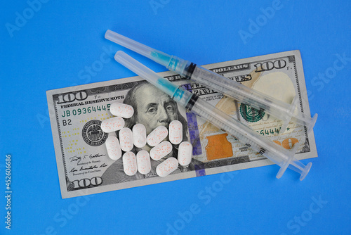 Hydrocodone tablets with syringes and a hundred dollar bill. Opiate addiction costs the U.S. economy $78.5 billion per year. photo