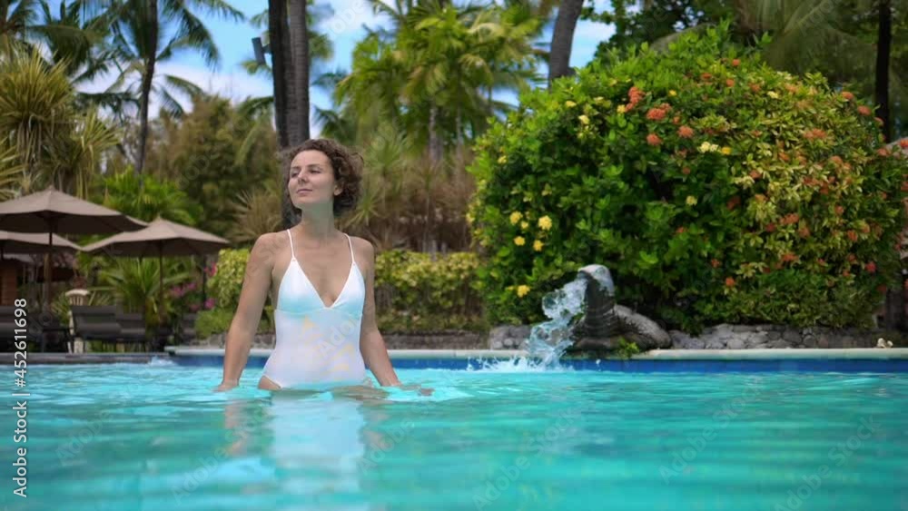 Beautiful white woman in enjoying the life standing in a swimming pool. Holidays in tropical paradise Beautiful white woman in enjoying the life standing in a swimming pool. Holidays in tropical paradise
