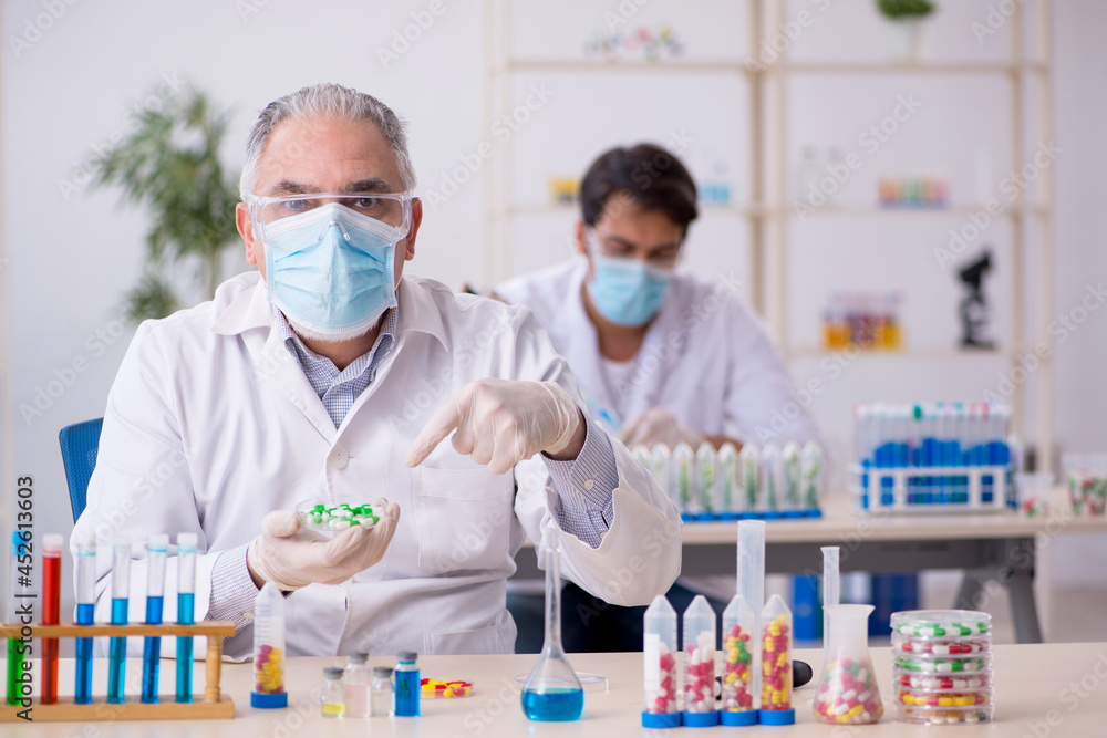 Two male chemists in drugs synthesis concept at the lab Two male chemists in drugs synthesis concept at the lab