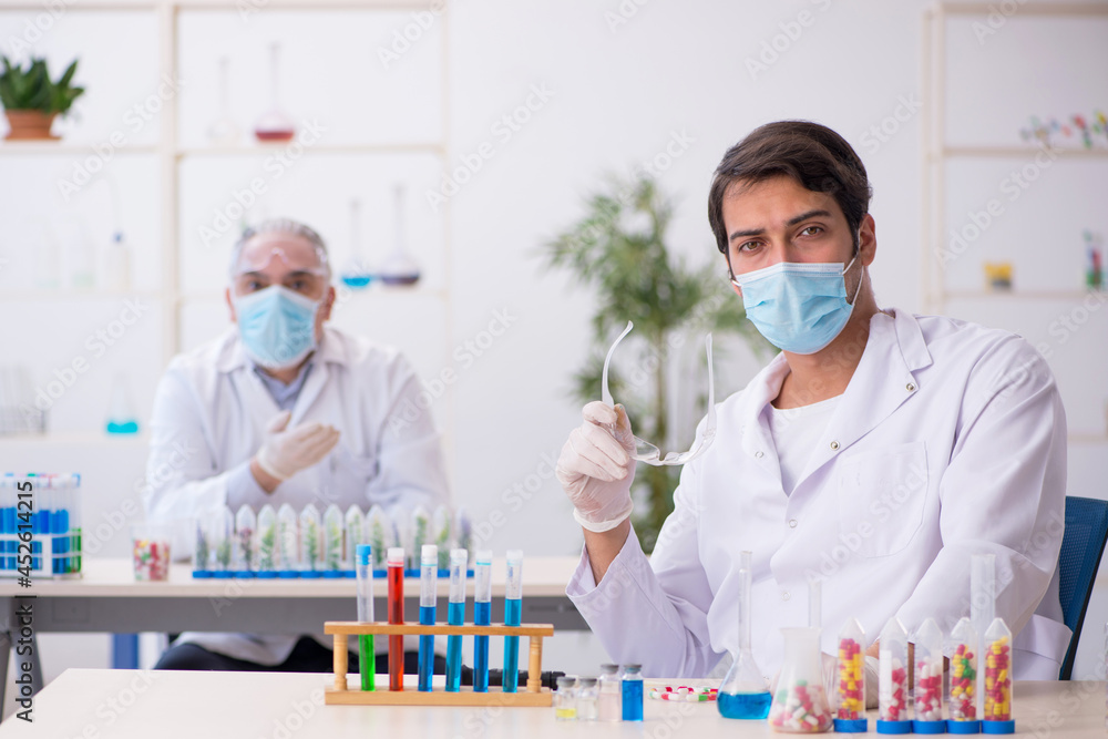 Two male chemists in drugs synthesis concept at the lab Two male chemists in drugs synthesis concept at the lab