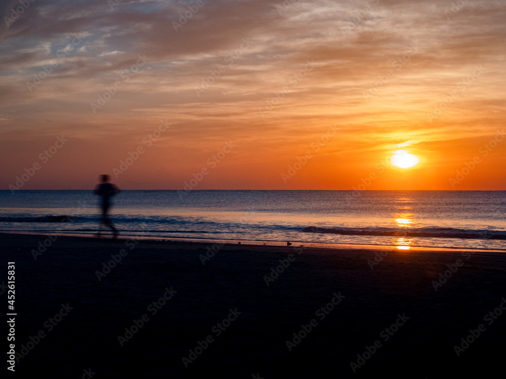 silhouette of a man running on the beach during sunrise