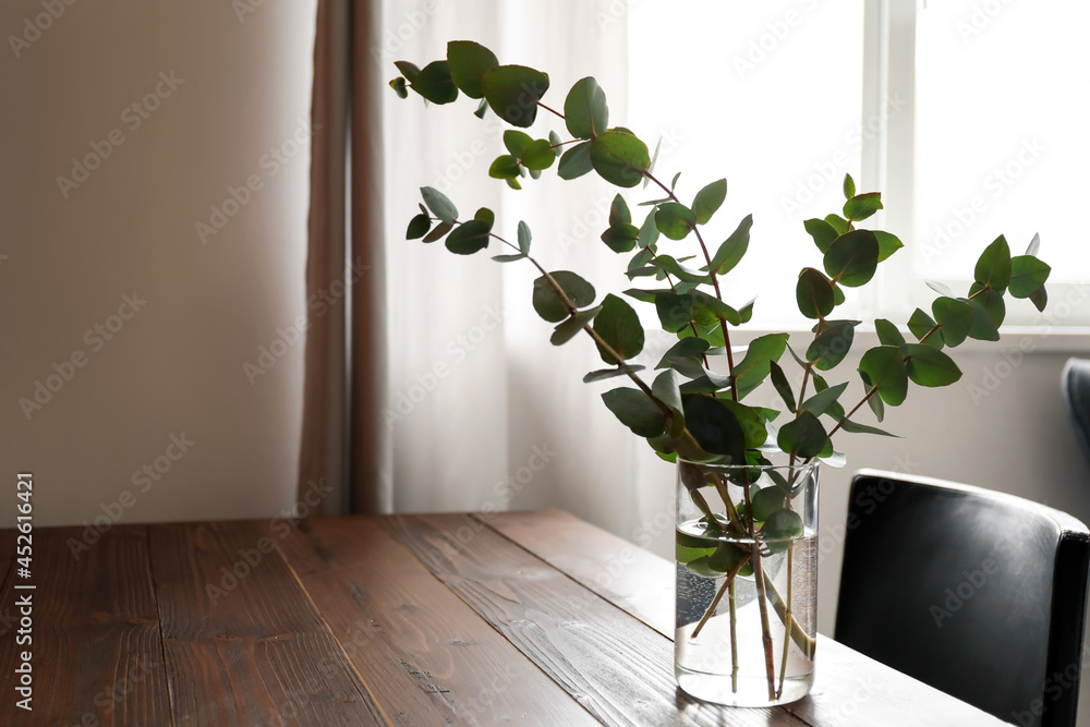 Vase with eucalyptus branches on table in room - obrazy, fototapety, plakaty 