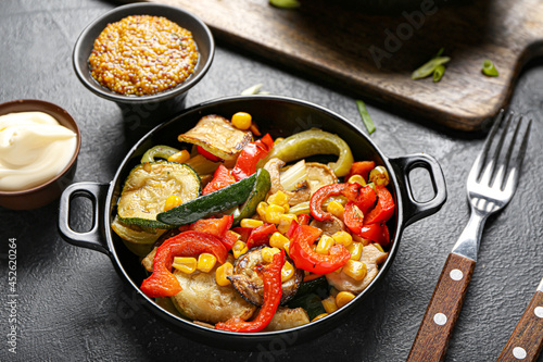 Frying pan with different vegetables and sauce on dark background, closeup