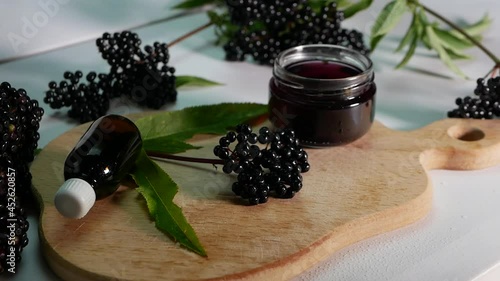 Black elderberry herbal medicine, ripe elderberry on a white background. in slow motion camera, medicinal herbal tincture