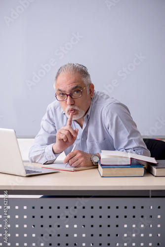 Old male teacher in front of whiteboard