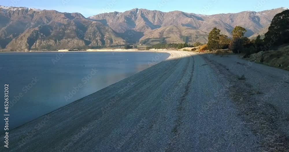 Wide smooth aerial along the beach at the south of Lake Hawea on New Zelands South Island, a popular swimming spot with locals and tourists alike. Wide smooth aerial along the beach at the south of Lake Hawea on New Zelands South Island, a popular swimming spot with locals and tourists alike.