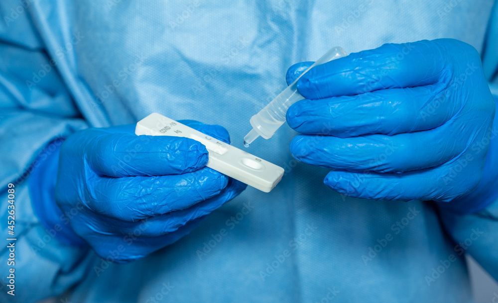 Close up of healthcare worker squeezing drops of fluid after doing nasal swab for testing covid-19 by antigen test kit. Rapid antigen testing is a screening tool to help detect COVID-19. Close up of healthcare worker squeezing drops of fluid after doing nasal swab for testing covid-19 by antigen test kit. Rapid antigen testing is a screening tool to help detect COVID-19.