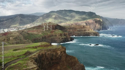 Madeira Islands, Portugal. Aerial footage of natural beauty with high volcanic cliffs and turquoise ocean. Wind turbines on the edge of a shore as seen from above. High quality 4k footage