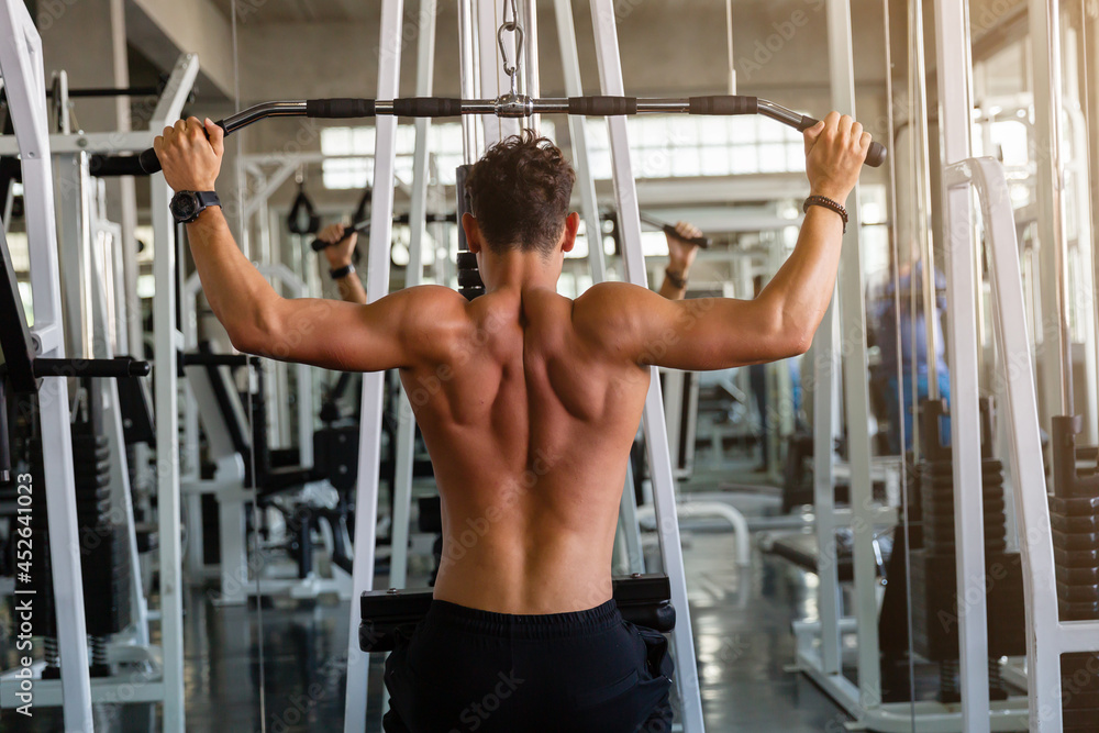 Young man doing workout exercise with thrust of the upper block in the gym, Athlete training hard of bodybuilding in the gym. Young man doing workout exercise with thrust of the upper block in the gym, Athlete training hard of bodybuilding in the gym.