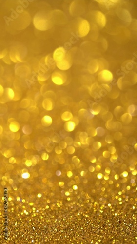 Gold Glitter Background. Magic dust, shiny texture, holiday lights, flying particles form a beautiful bokeh. Shining festive Christmas backdrop. Vertical © Fevziie