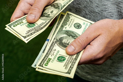 a man counts money a bundle of hundred dollar bills