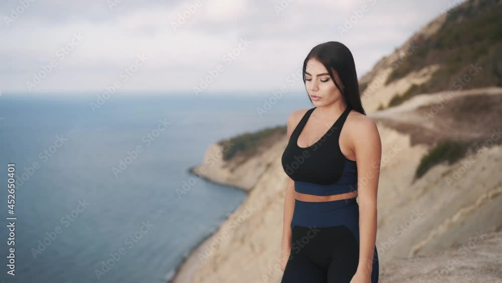 Slow motion beautiful slim sexy caucasian woman walks on the cliff and enjoys the sea air while admiring the sea waves. Travel and outdoor activities concept Slow motion beautiful slim sexy caucasian woman walks on the cliff and enjoys the sea air while admiring the sea waves. Travel and outdoor activities concept