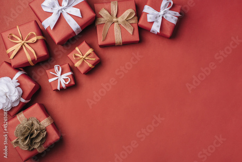 Gift boxes with white and brown bows on a red backdrop.