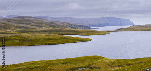 Panoramic image of a landscape with a lake, a fjord and mountains on the isle of Mageroya in northern Norway