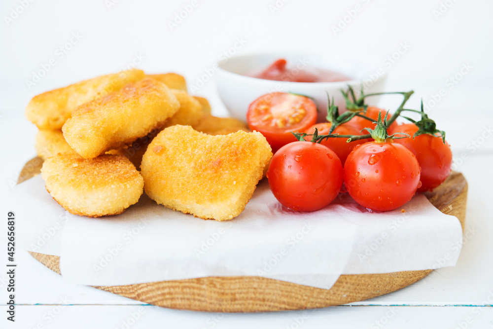 Homemade chicken nuggets with sauce and tomatoes on a wooden board Homemade chicken nuggets with sauce and tomatoes on a wooden board