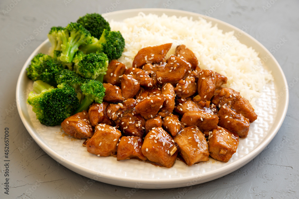 Homemade Teriyaki Chicken with Rice and Broccoli on a plate on a gray surface, side view. Close-up. Homemade Teriyaki Chicken with Rice and Broccoli on a plate on a gray surface, side view. Close-up.