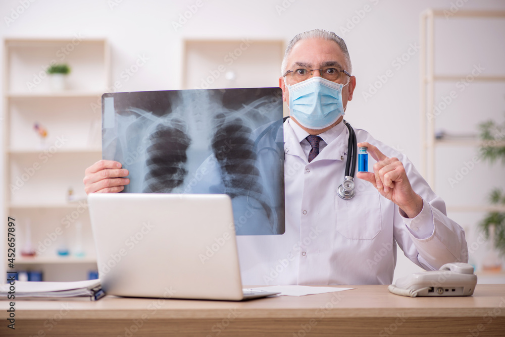 Old male doctor radiologist working in the clinic during pandemi