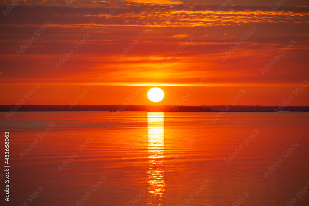 Bright red sunset with a sunny path on the water. Svir river, Leningrad region, Russia.