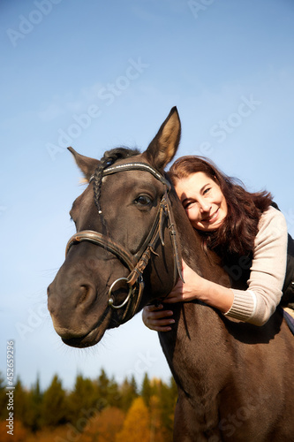 Woman riding a horse in filed in autumn day and blue sky background © keleny