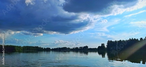 Flat lake, against the background of a forest and a clear, blue sky