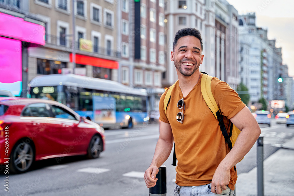 Young smiling Latino man walking through the streets of Madrid. Walking down main street of the city. Young smiling Latino man walking through the streets of Madrid. Walking down main street of the city.